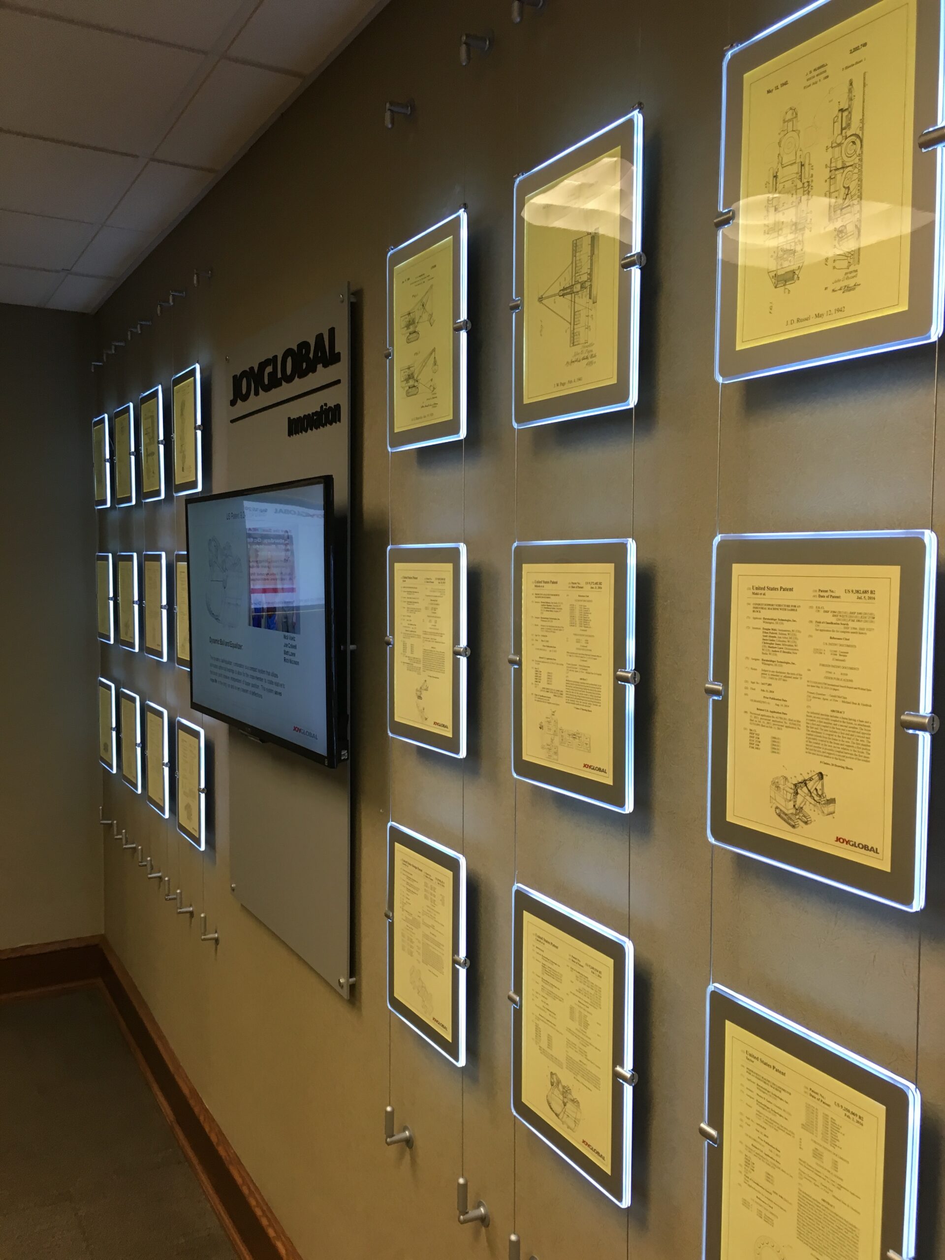 Wall displaying framed certificates and a monitor in an office setting.