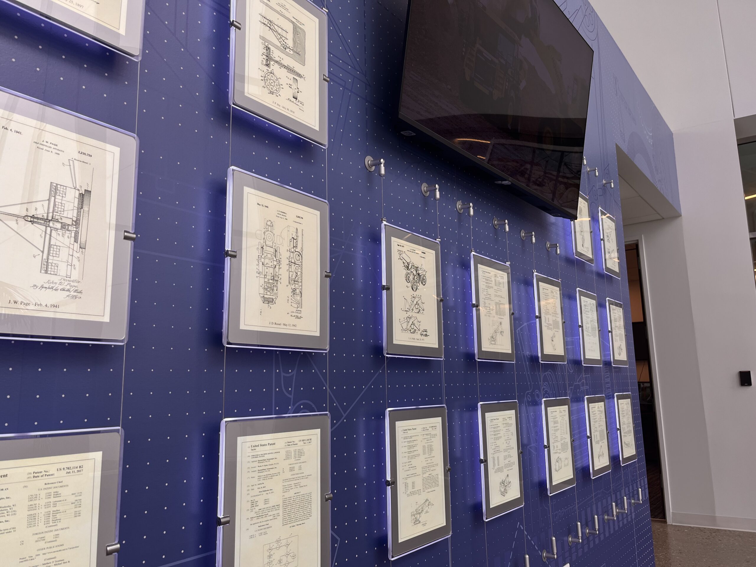 A wall display of framed certificates beneath a mounted TV.