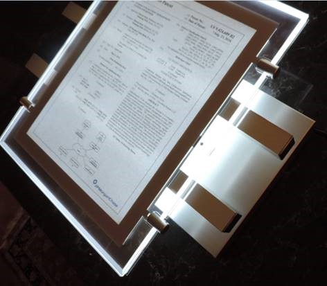 Framed menu displayed on a restaurant table with a napkin holder nearby.