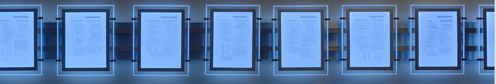 Three framed documents displayed on a wall with backlighting.