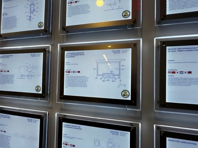 Framed certificates displayed on a wall with glowing backlight.