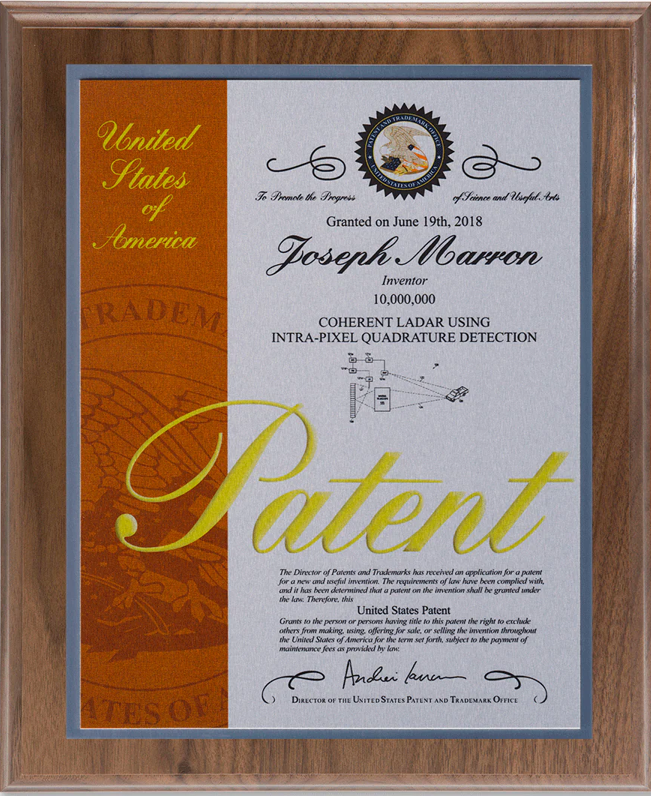 A framed U.S. patent certificate with decorative text and signatures.